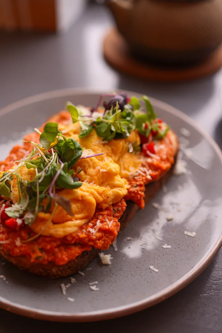 Toast with scrambled eggs and microgreens on a grey plate